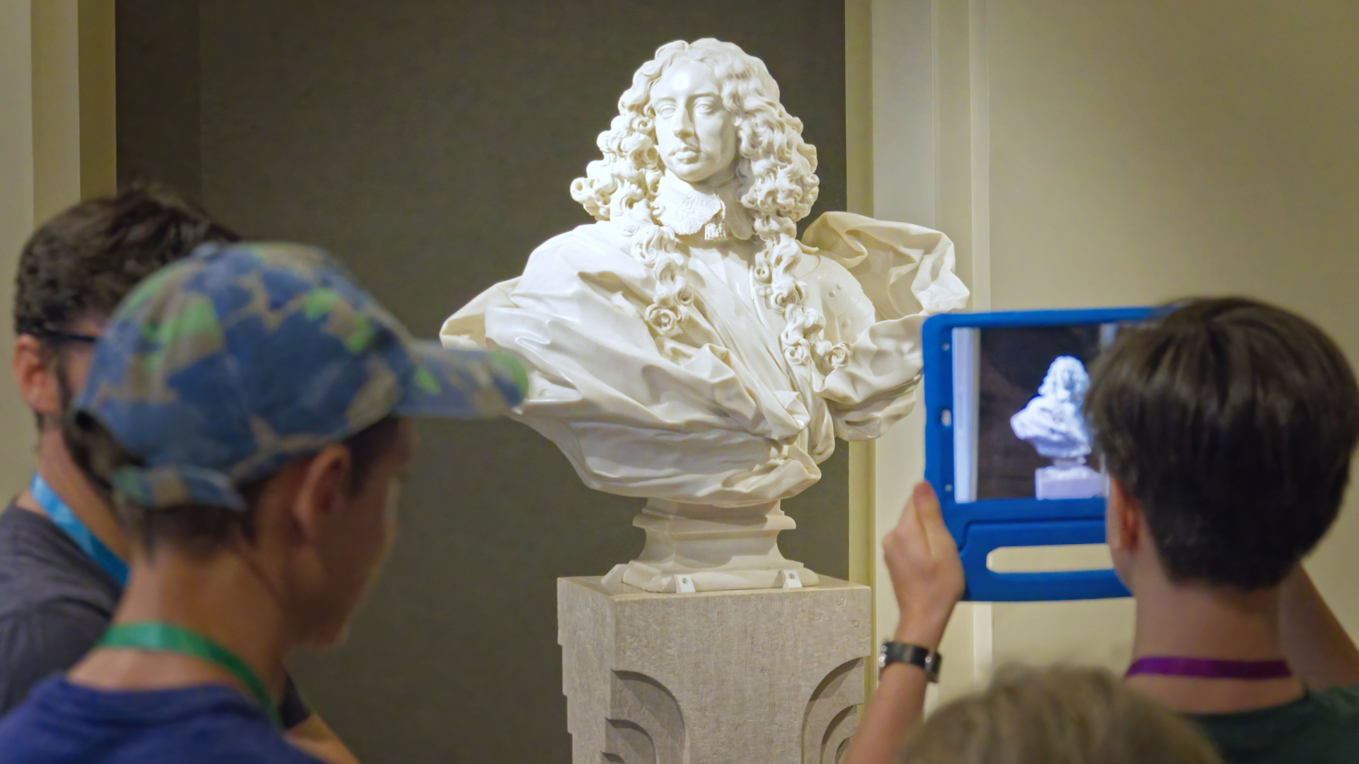 Ragazzi ripresi di spalle che riprendono il busto di Francesco I d'Este con i tablet