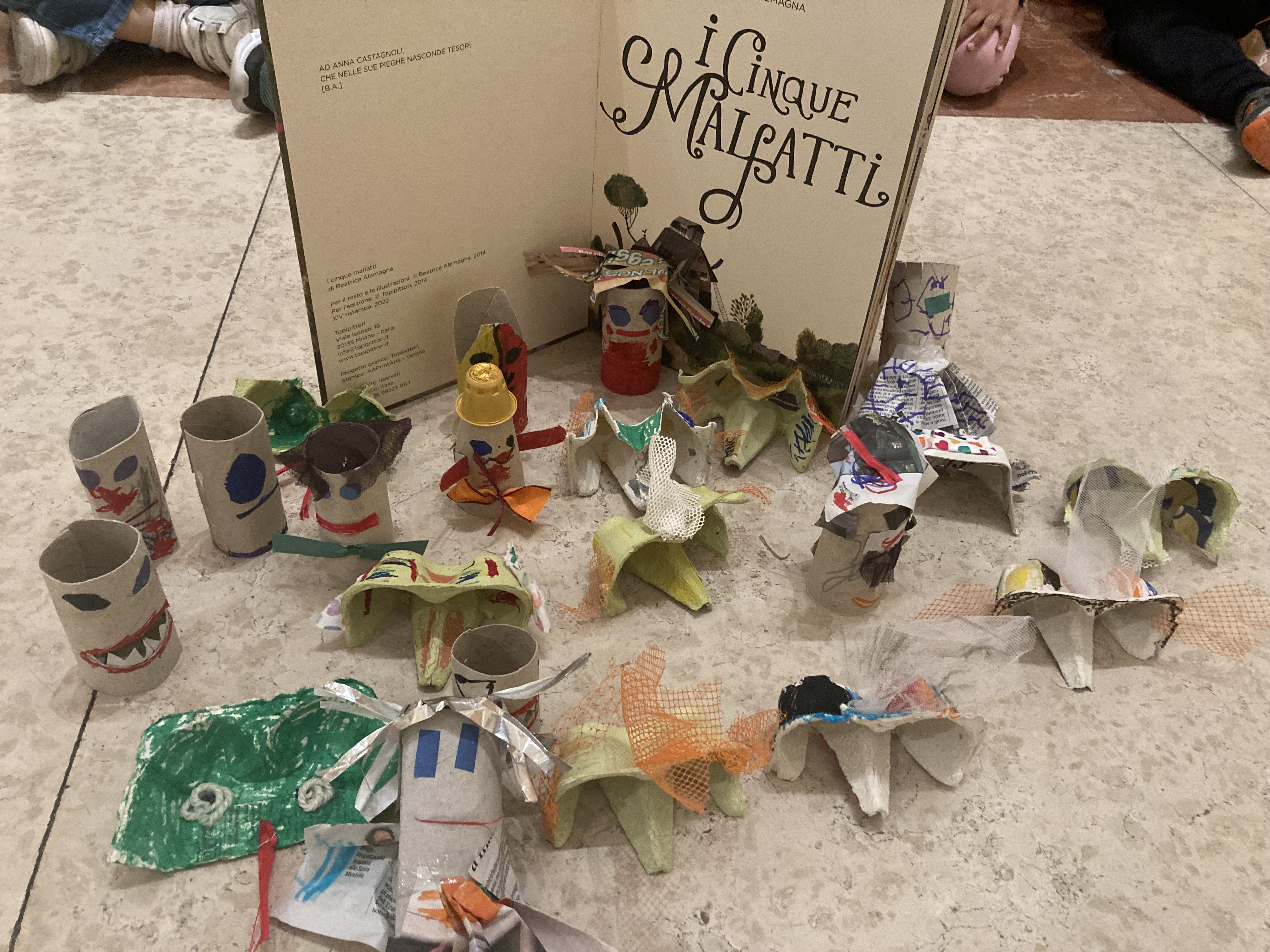 Il libro de "I cinque malgatti" aperto e vicino i lavori prodotti nel laboratorio dai bambini.