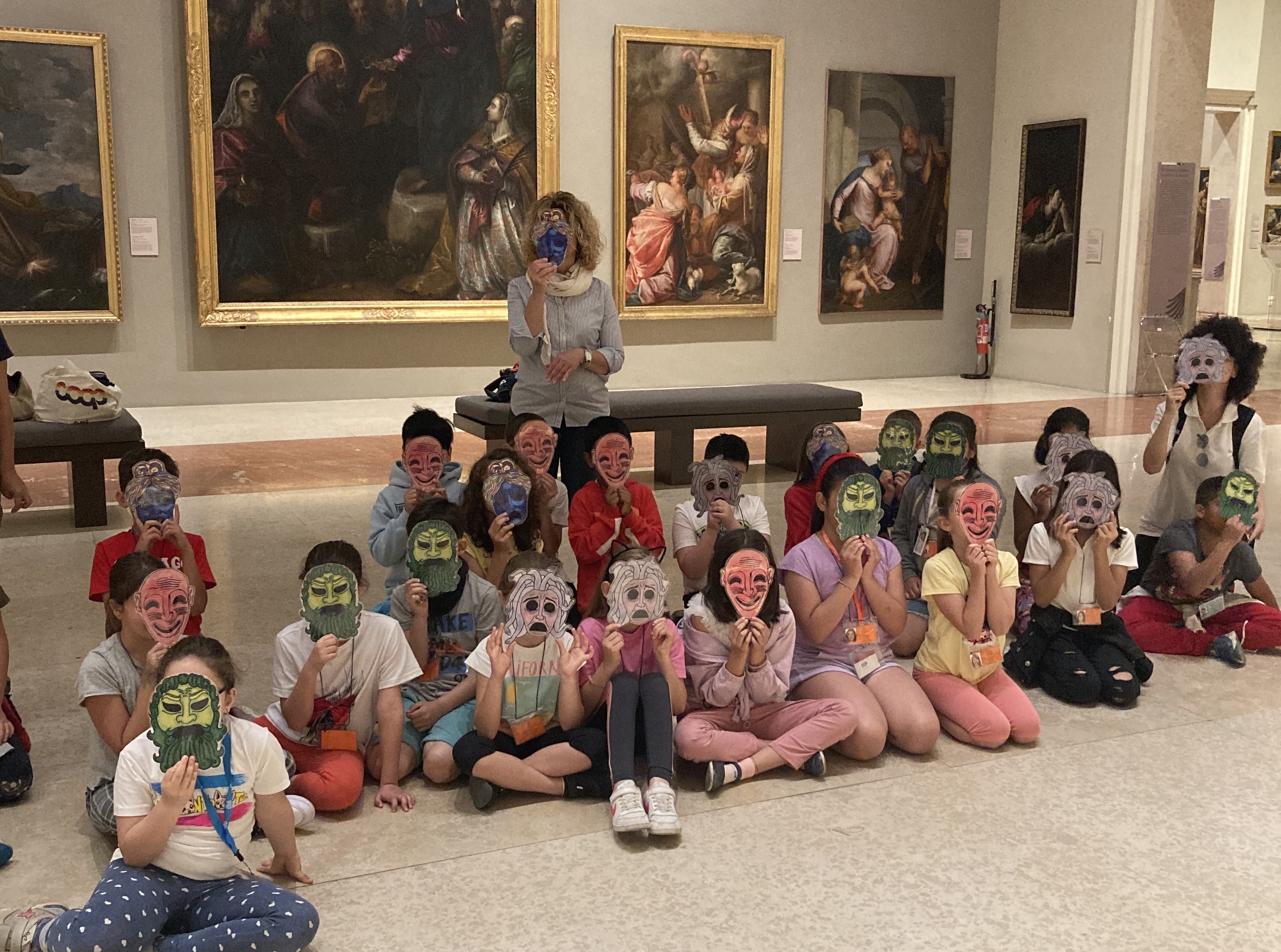 Una classe in una sala delle Gallerie Estensi con una maschera appoggiata sul viso.