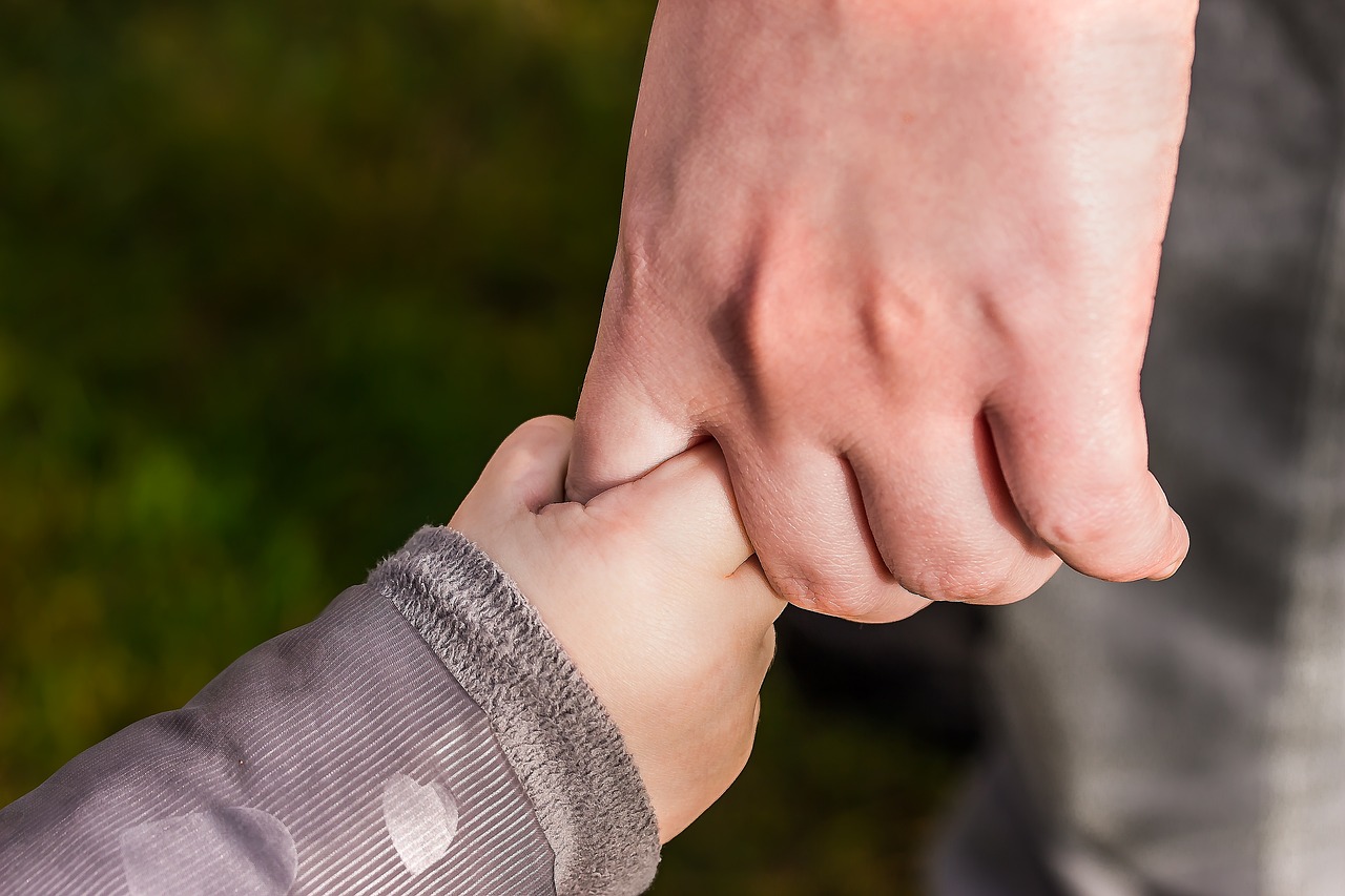 Mano di adulto che stringe la mano di un bambino