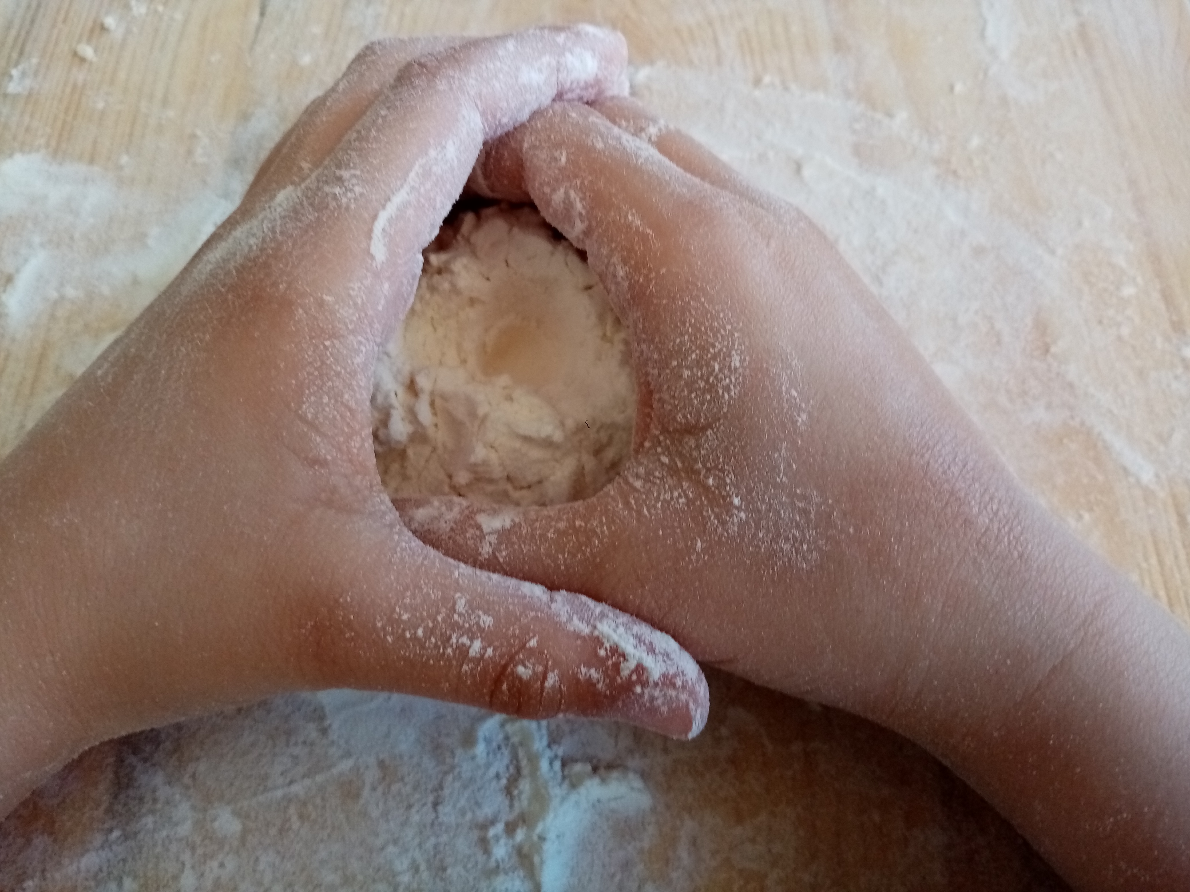 Le mani di un bambino che impastano della farina.