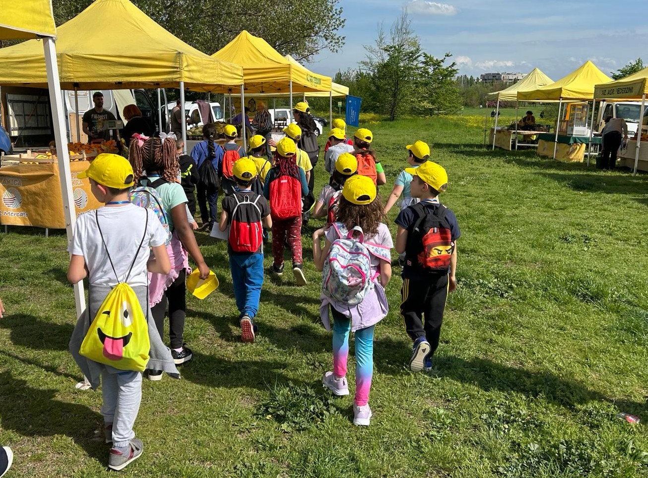 Gruppo di bambini in cammino verso le bancarella di un mercato contadino.