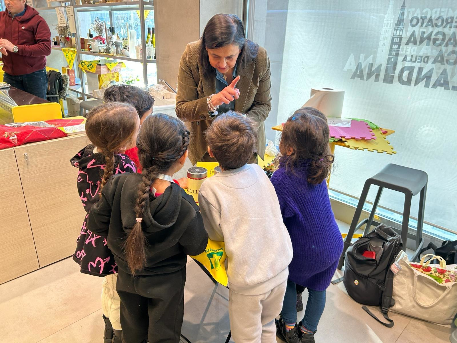 Gruppo di bambini che svolgono un'attività in piedi, attorno a un tavolo guidati dall'operatore.