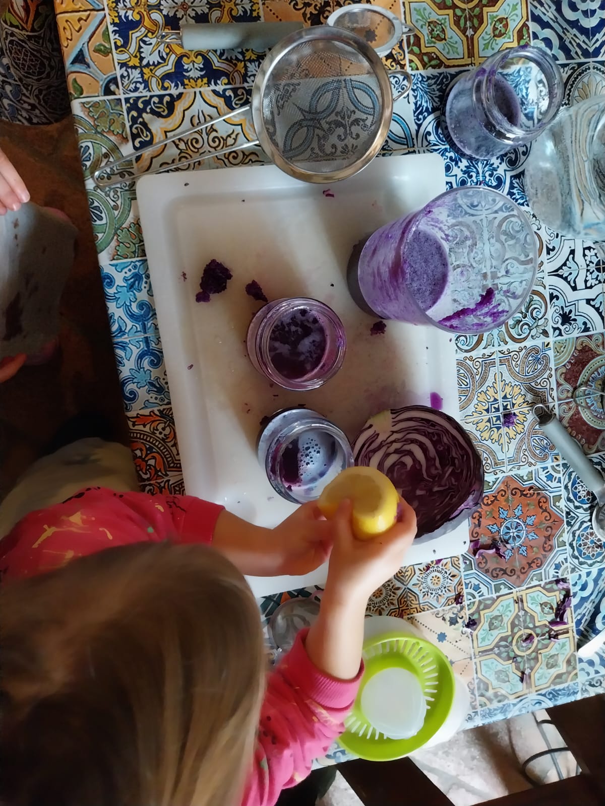 Un bambino sperimenta la preparazione di colori naturali con frutta e verdura, colini, spremiagrumi e tanti contenitori