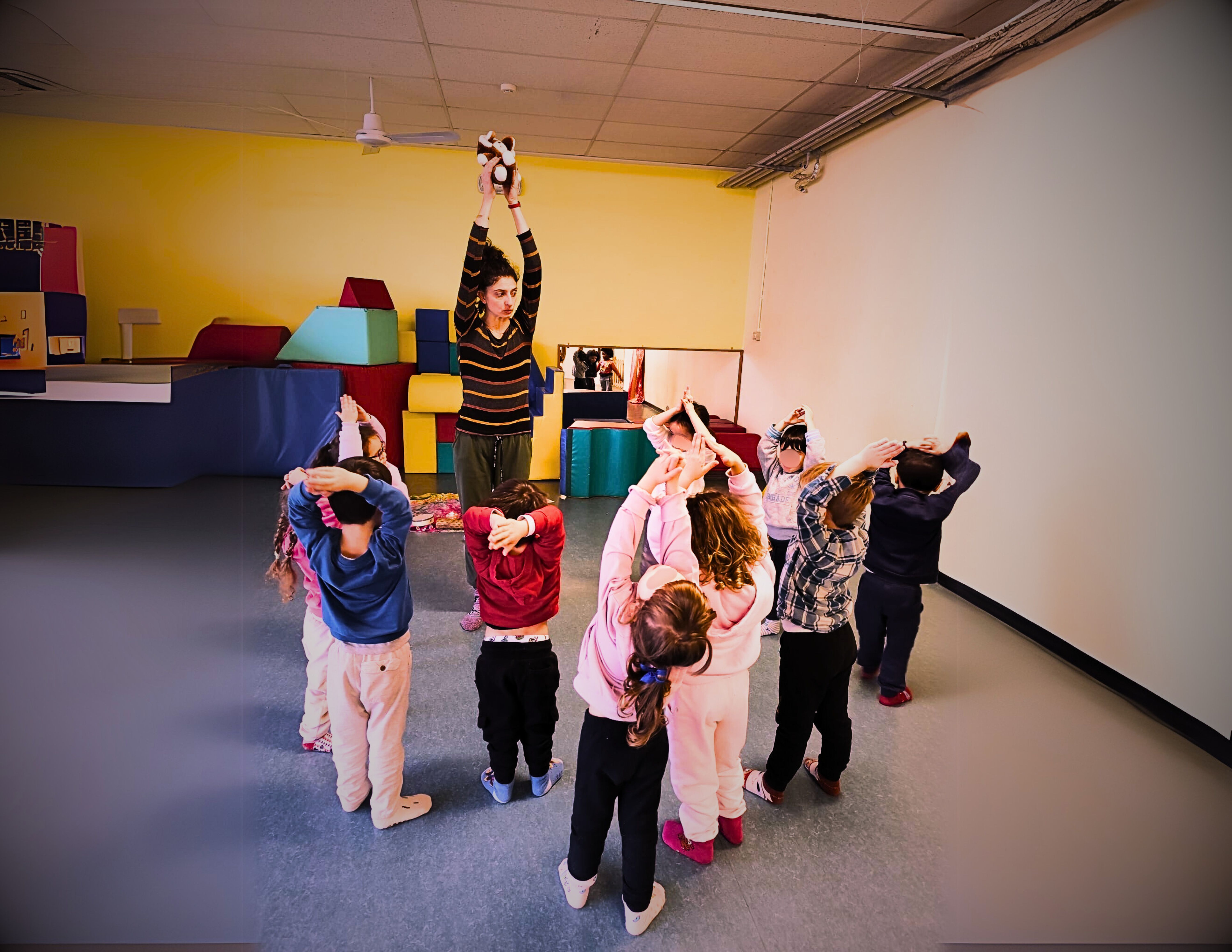 Un'aula con bambini e la conduttrice che giocano con lo yoga.