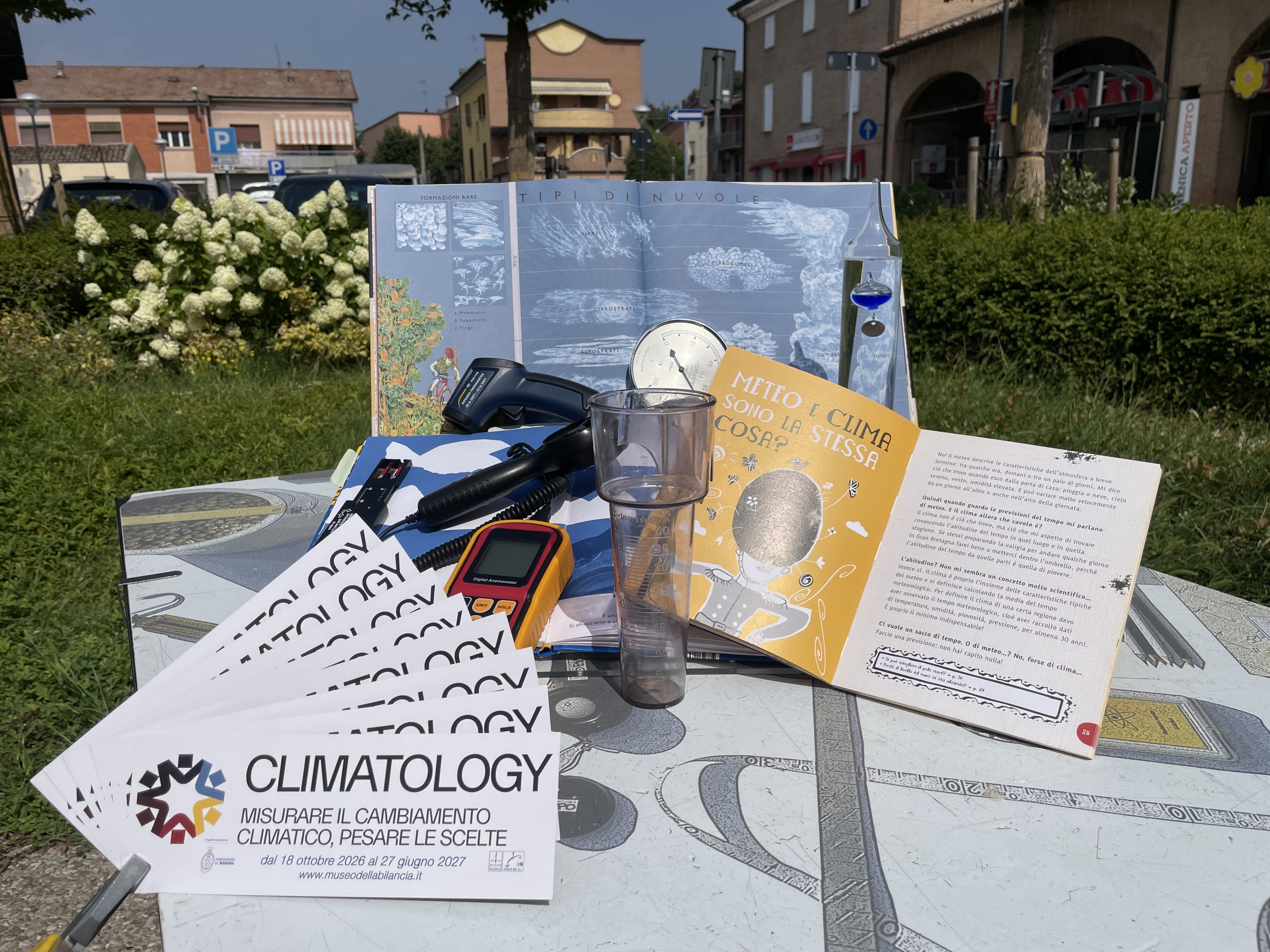 Un tavolino su cui sono esposti volantini sul cambiamento climatico e strumenti di misurazioni del clima.