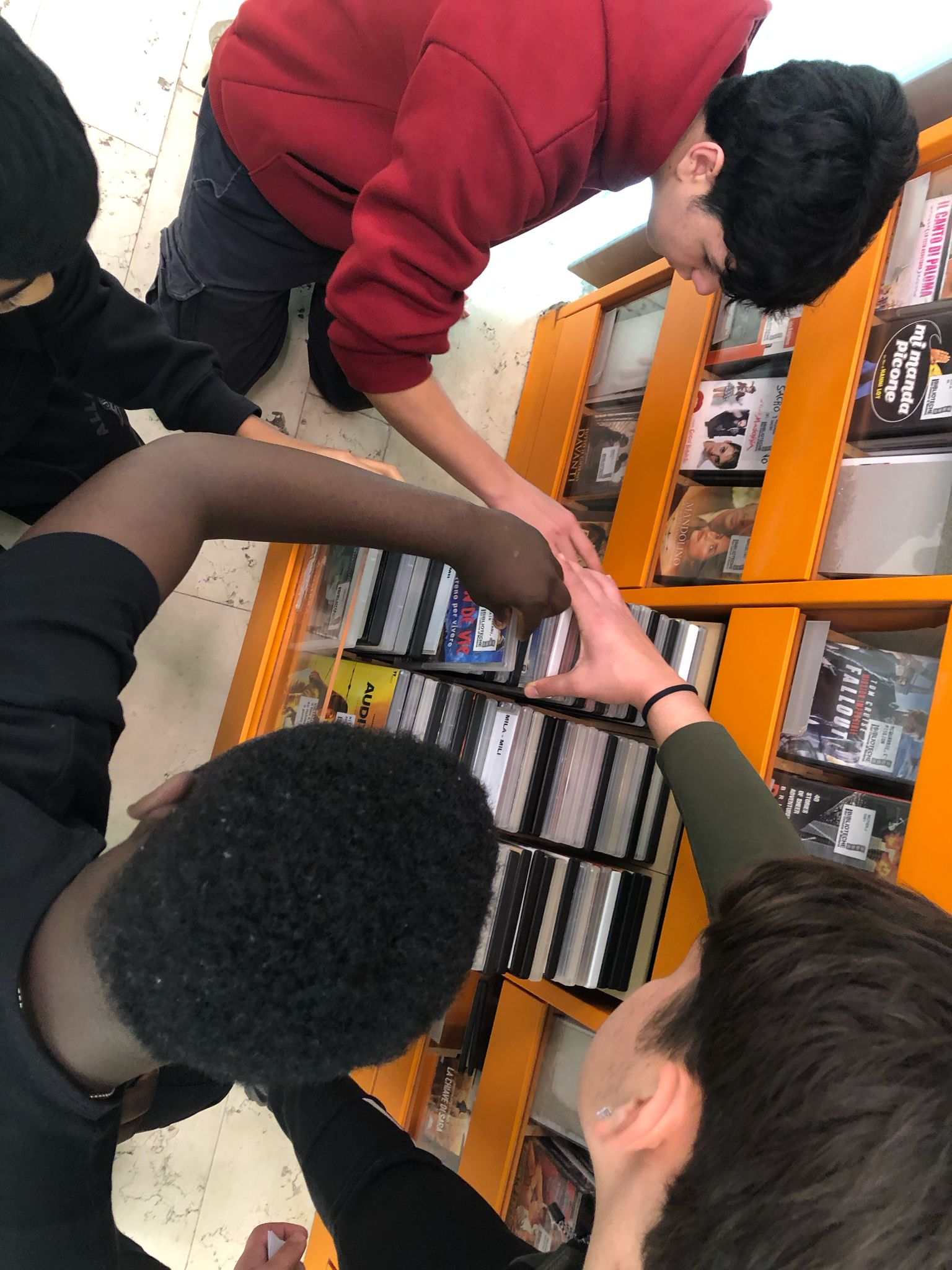 Studenti che cercano dei DVD in un raccoglitore della biblioteca.